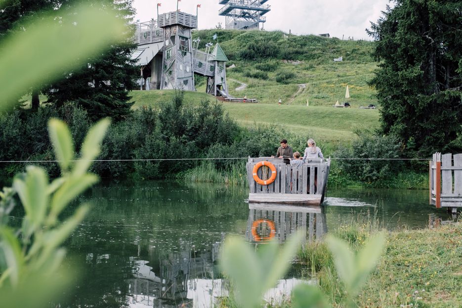 Familie fährt auf Floß über Geistersee mit Geisterschloss im Hintergrund