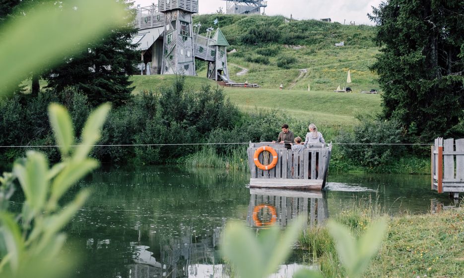 Familie fährt auf Floß über Geistersee mit Geisterschloss im Hintergrund