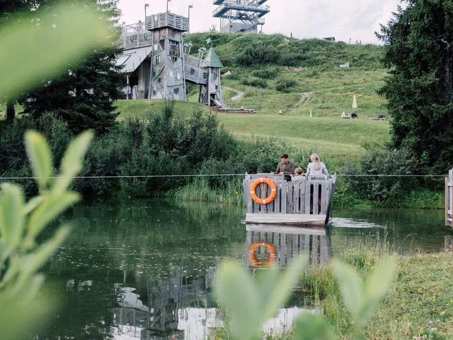 Familie fährt auf Floß über Geistersee mit Geisterschloss im Hintergrund