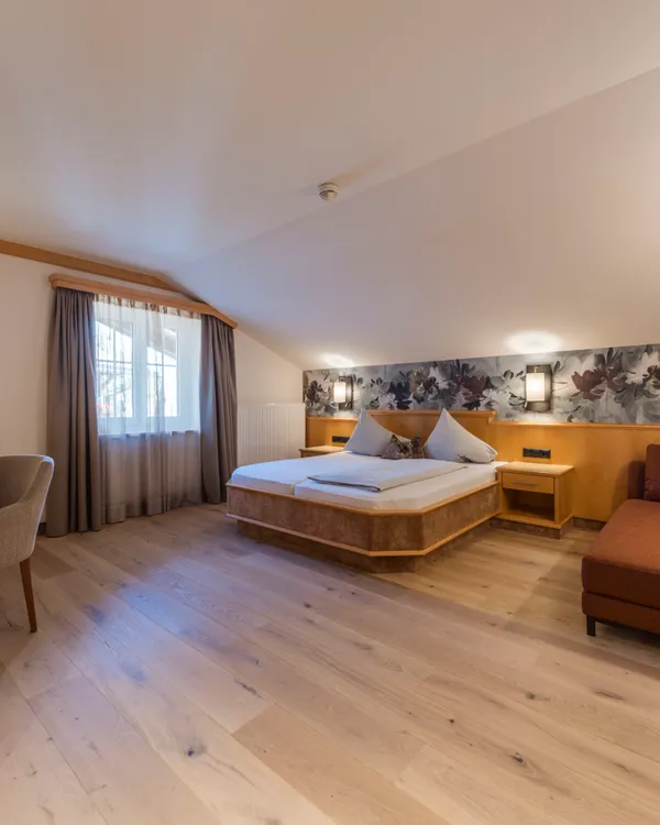 Gemütliches Hotelzimmer mit Doppelbett, Sofa und Schreibtisch am Fenster