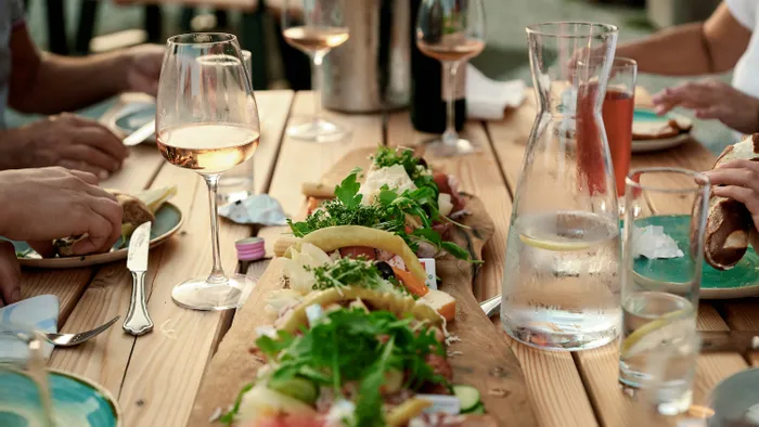 Outdoor dining with charcuterie board, wine glasses, and people enjoying food