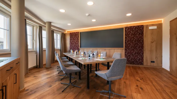 Moderna sala conferenze con pavimento in legno, grande tavolo, sedie e bevande in bottiglia