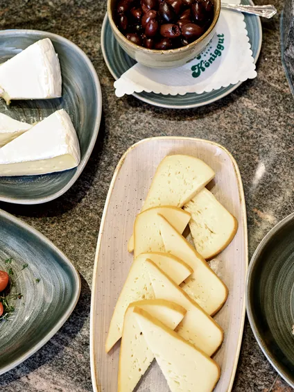 Selezione di formaggi gourmet e olive nere serviti su piatti in ceramica su piano in pietra