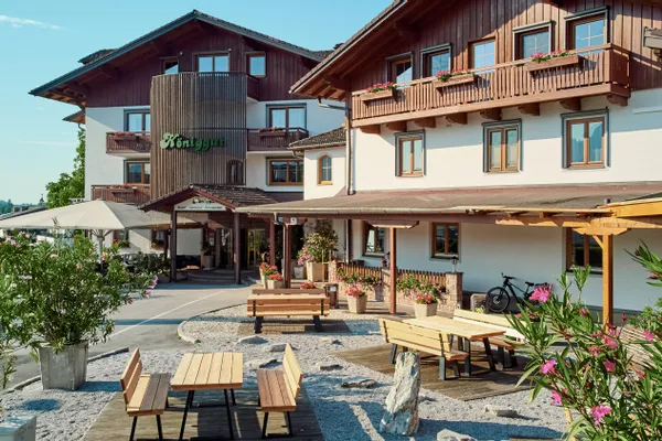Traditionelles Alpenhotel mit Holzbalkonen, Sitzbereich im Freien und blühenden Pflanzen
