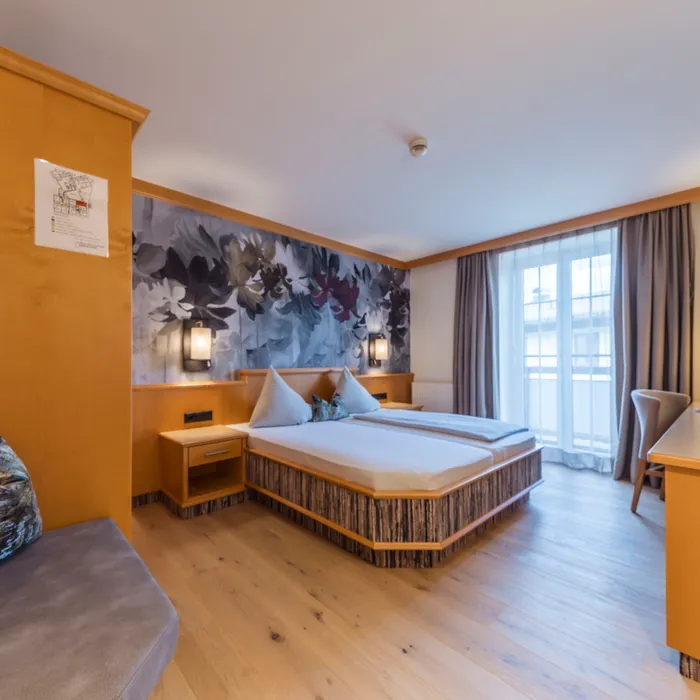 Modernes Hotelzimmer mit Doppelbett, Blumenmuster und Holzboden