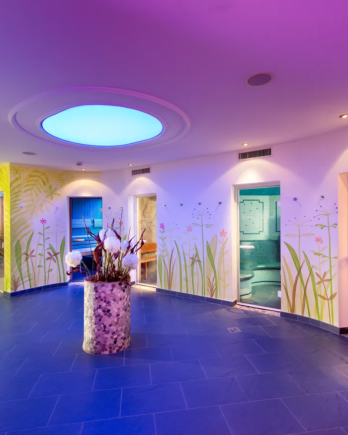 Area benessere colorata con bagno turco a mosaico, porte della sauna e decorazioni floreali