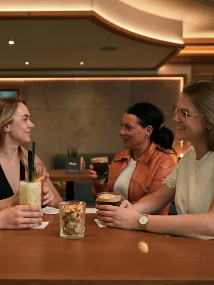 Vier Frauen genießen Getränke und unterhalten sich an einem modernen Cafétisch