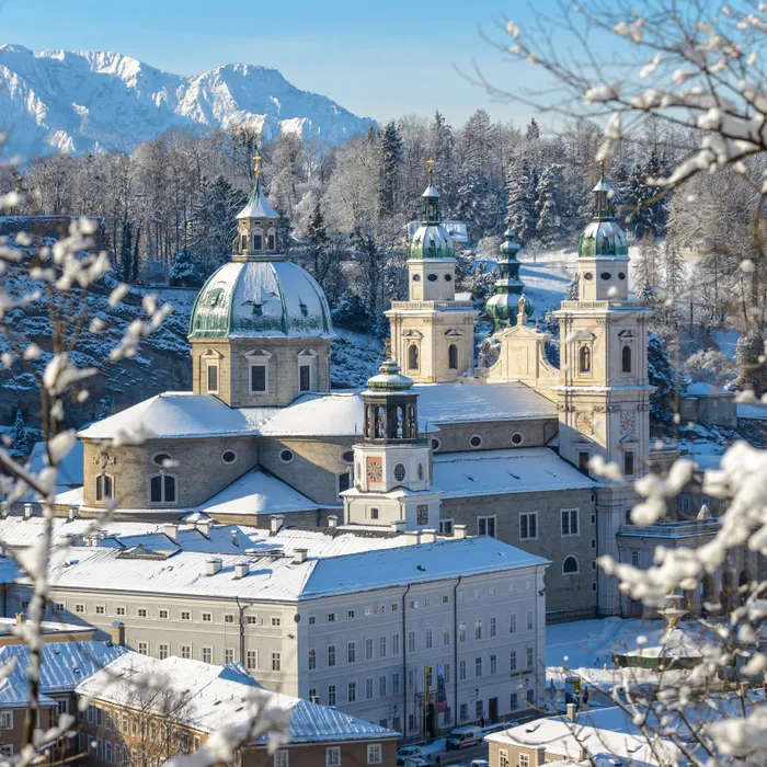 Snow-covered Salzburg Cathedral with Alpine mountains in the background
