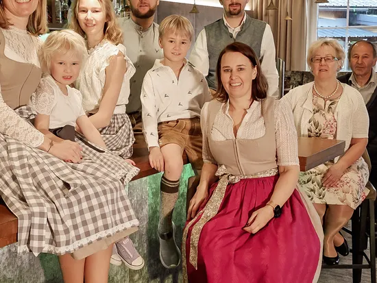 Familie in traditioneller Alpenkleidung posiert gemeinsam in modernem Barbereich