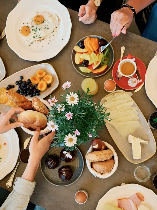 Vielfältiger Frühstückstisch mit Eiern, Käse, Aufschnitt, frischem Obst, Brötchen und Kaffee