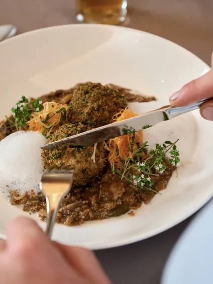 Gourmet-Veggiegericht mit Kräuterknödeln, Schaum, Pilzen und Microgreens