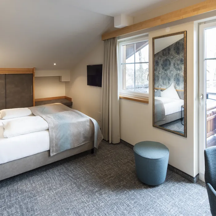 Modernes Hotelzimmer mit Doppelbett, Balkonzugang und stilvoller Einrichtung