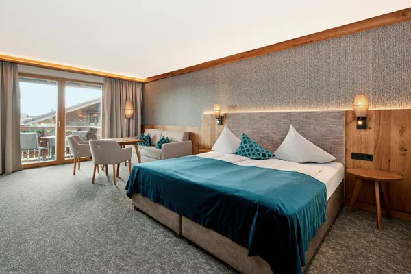 Moderna camera d'albergo con letto matrimoniale, area salotto e accesso al balcone