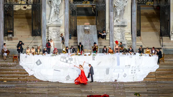 Spettacolo teatrale all'aperto con attori in costume a un lungo banchetto sui gradini della cattedrale