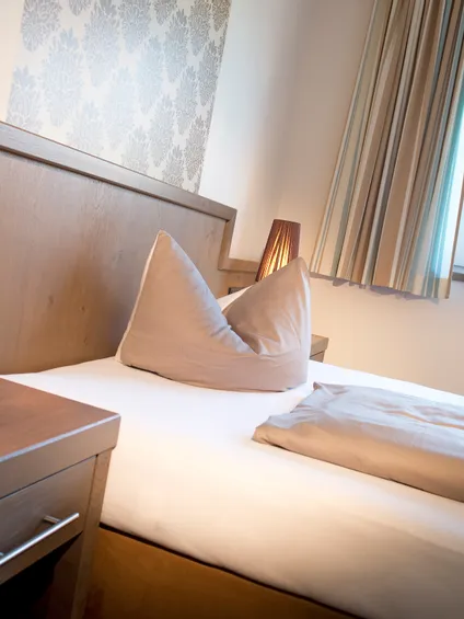 Gemütliches Hotelzimmer mit Einzelbett, Nachttischlampen und Tageslicht vom Fenster