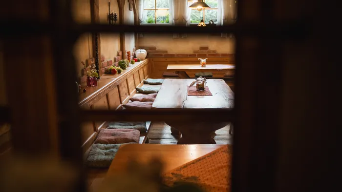 Sala da pranzo rustica in legno con panche imbottite e frutta decorativa sul davanzale