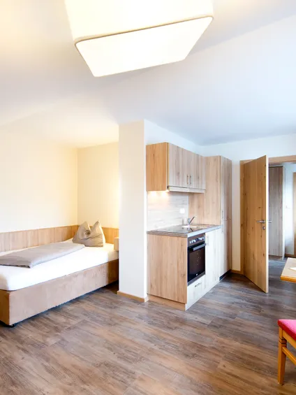 Helles Studio-Apartment mit Einzelbett, Küchenzeile, Esstisch und Holzmöbeln