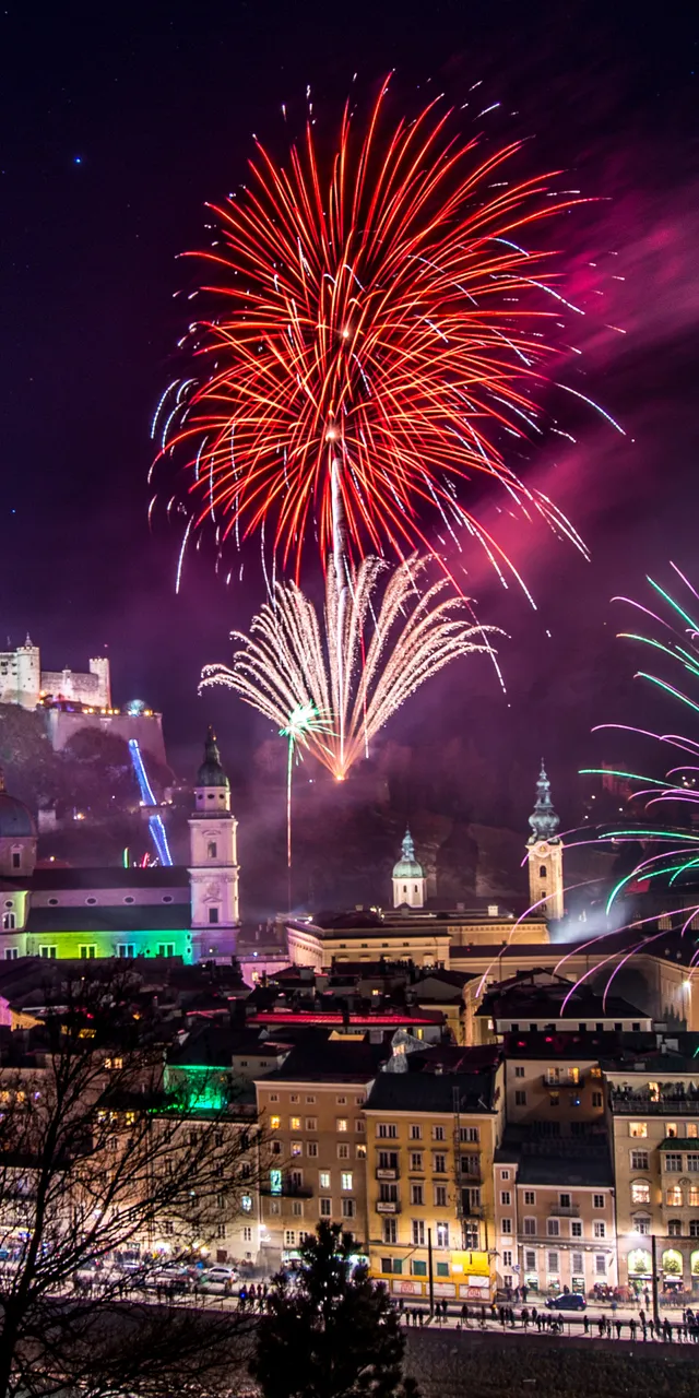 Bunte Feuerwerke über Salzburg bei Nacht mit der Festung Hohensalzburg im Hintergrund