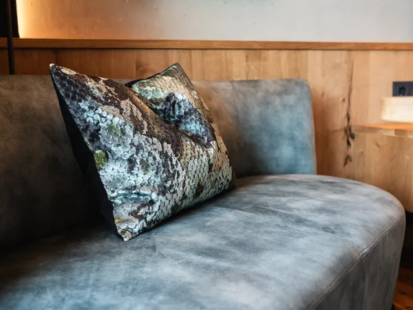 Modernes graues Samtsofa mit dekorativen Paillettenkissen in gemütlichem Wohnzimmer