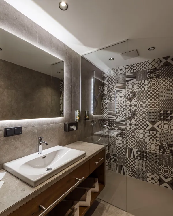 Modern bathroom with illuminated mirror and patterned tile shower