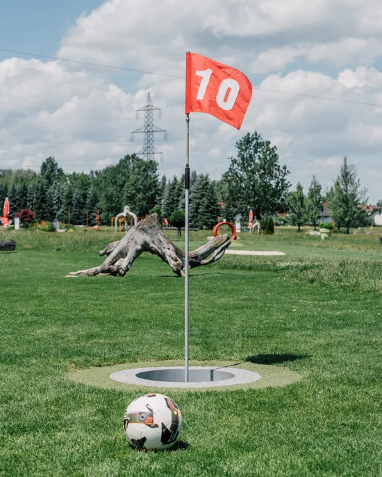 Footgolf course with red flag number 10 and a soccer ball on grass