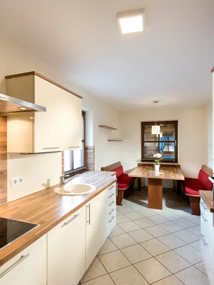 Moderne Küche mit Holzarbeitsplatten, Keramikkochfeld und gemütlicher Essecke mit roten Bänken