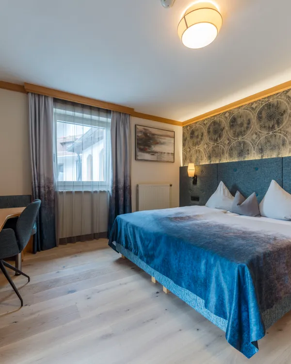 Modern hotel room with double bed, desk, and stylish decor