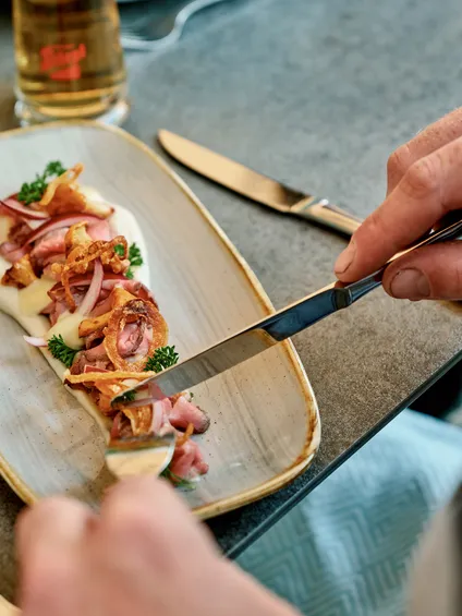 Gourmet-Rinderbraten mit Zwiebeln, Petersilie und cremiger Soße auf Keramikteller