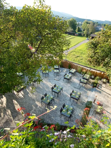 Restaurantterrasse im Freien mit grüner Tischdeko, umgeben von Bäumen und Landschaft