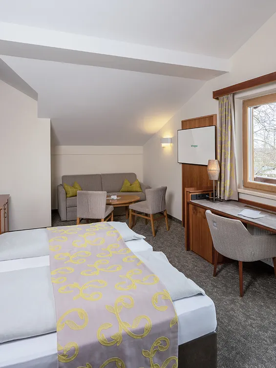 Gemütliches Hotelzimmer mit Doppelbett, Sitzecke, Schreibtisch und Balkonblick