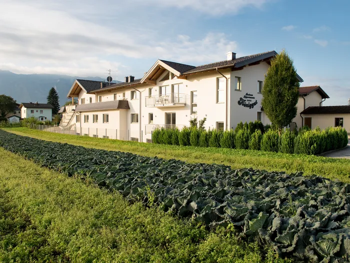 Kohlfeld vor einem Gästehaus mit Bergen im Hintergrund