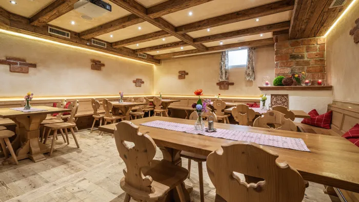 Gemütlicher rustikaler Restaurantinnenraum mit Holzmöbeln, Blumendeko und stimmungsvoller Beleuchtung