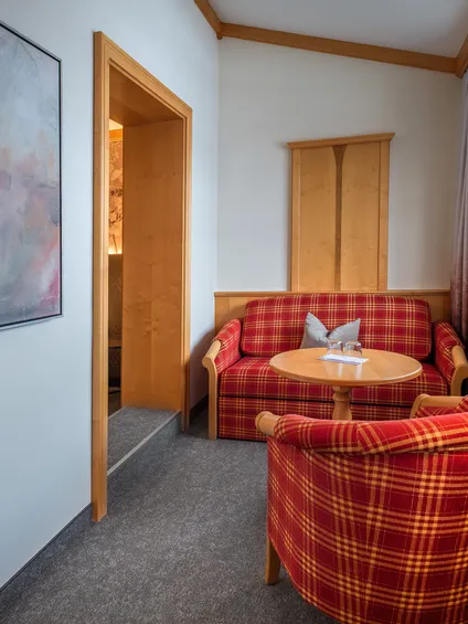 Accogliente area salotto d’hotel con poltrone scozzesi rosse, tavolo rotondo e luce calda