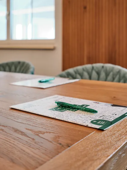 Conference table with notepads and green pens in a modern meeting room
