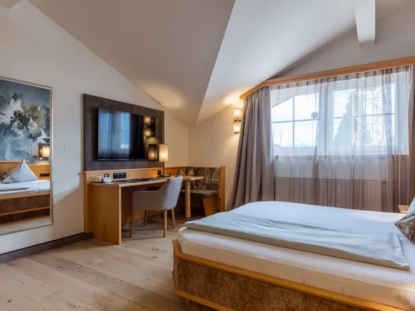 Accogliente camera d'hotel con letto matrimoniale, TV, scrivania e finestra