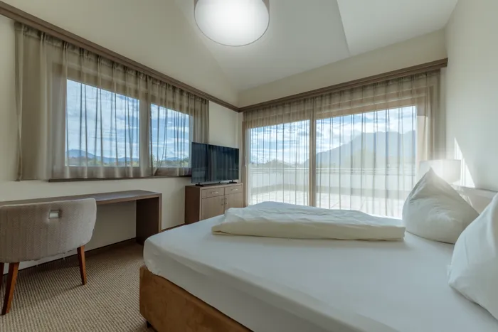 Luminoso hotel con grandi finestre, un letto e una TV a schermo piatto