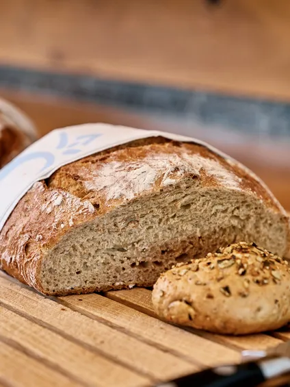 Frisch geschnittenes Bauernbrot und Körnerbrötchen auf Holzbrett