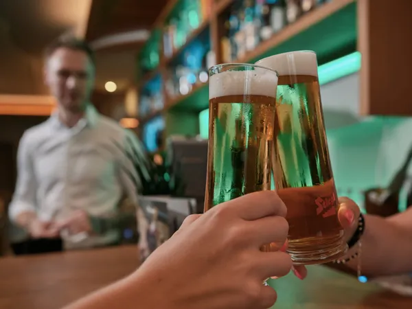 Zwei Personen stoßen mit Stiegl-Biergläsern an der Bartheke an