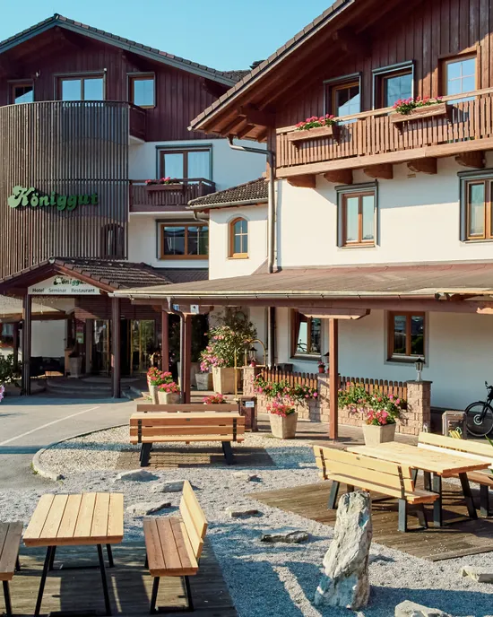 Traditionelles Alpenhotel mit Holzbalkonen, Sitzbereich im Freien und blühenden Pflanzen