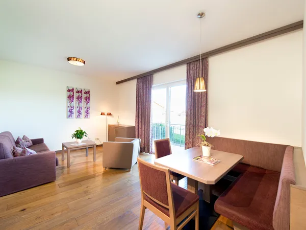Luminoso soggiorno e sala da pranzo moderni con pavimento in legno e decorazioni con orchidee