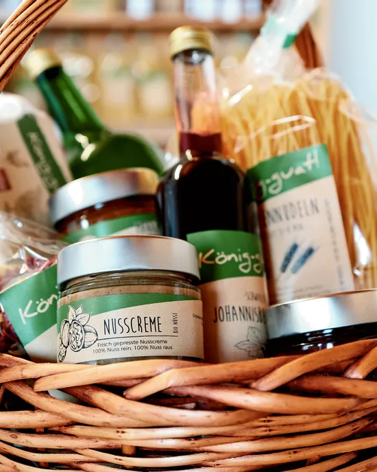 Wicker basket filled with organic food products like nut spread, pasta, juice, and preserves