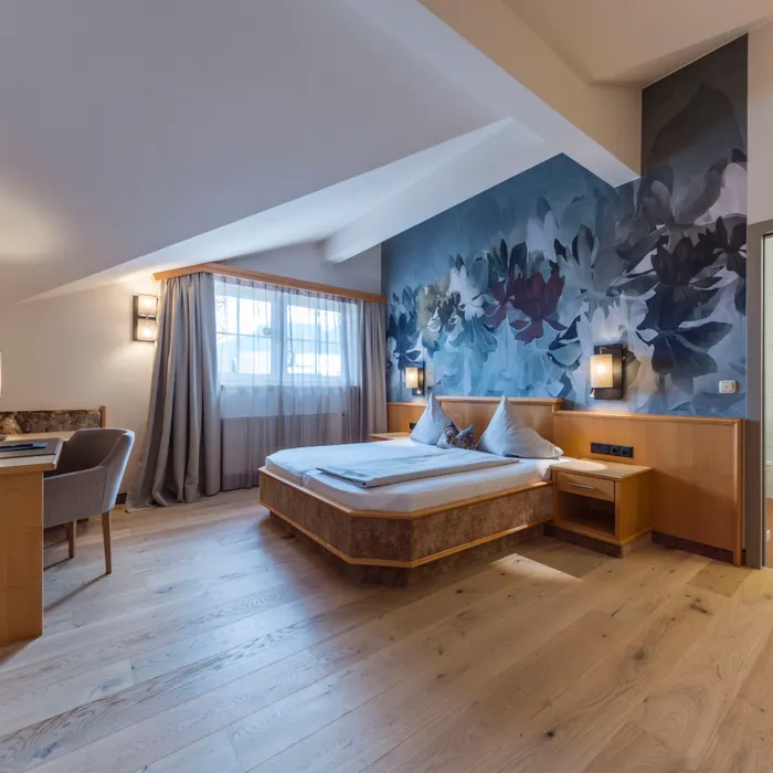 Modernes Hotelzimmer mit Doppelbett, Blumendekor und Holzboden