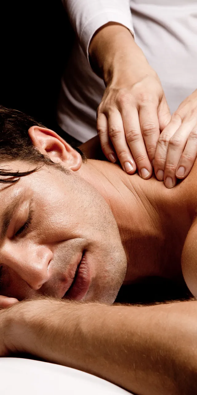 Mann genießt eine entspannende Schultermassage im Spa