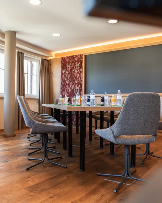 Sala conferenze moderna con pavimento in legno, sedie grigie e bevande sul tavolo riunioni