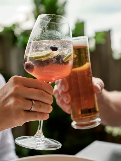 Freunde stoßen mit Cocktail und Bier auf einer Außenterrasse an