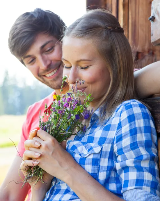 Smiling couple embracing while woman holds and smells wildflower bouquet