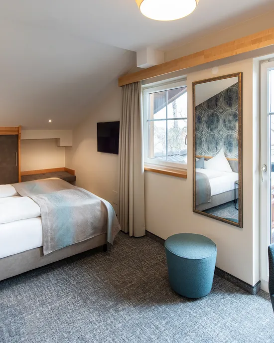 Modern hotel room with double bed, desk, balcony access and soft lighting