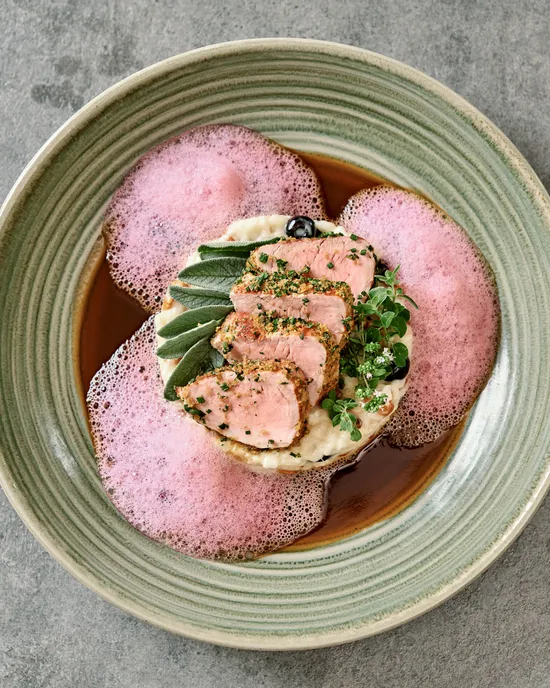 Gourmet-Schweinefilet mit rosa Schaum, Kartoffelpüree und Kräutern auf Keramikteller
