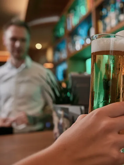 Zwei Personen stoßen mit Stiegl-Biergläsern an der Bartheke an