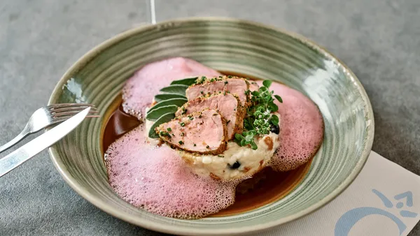 Gourmet-Schweinefilet auf Risotto mit rotem Schaum und Kräutern, serviert mit Weißwein